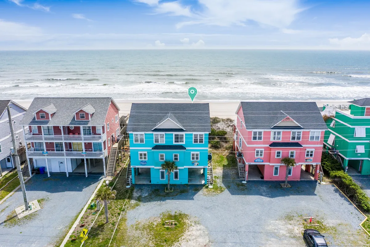 A group of colorful beach houses facing the ocean, with a wide, sandy beach inviting visitors to relax, play, and enjoy the waterside ambiance. The ocean view is front and center, promising romantic moments and relaxation for couples.